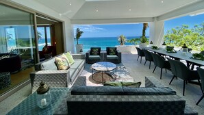 A modern outdoor living area with a glass ceiling, a dining table, and comfortable seating. - Clifton YOLO Spaces – Clifton Mansion Villa (Cape Town)