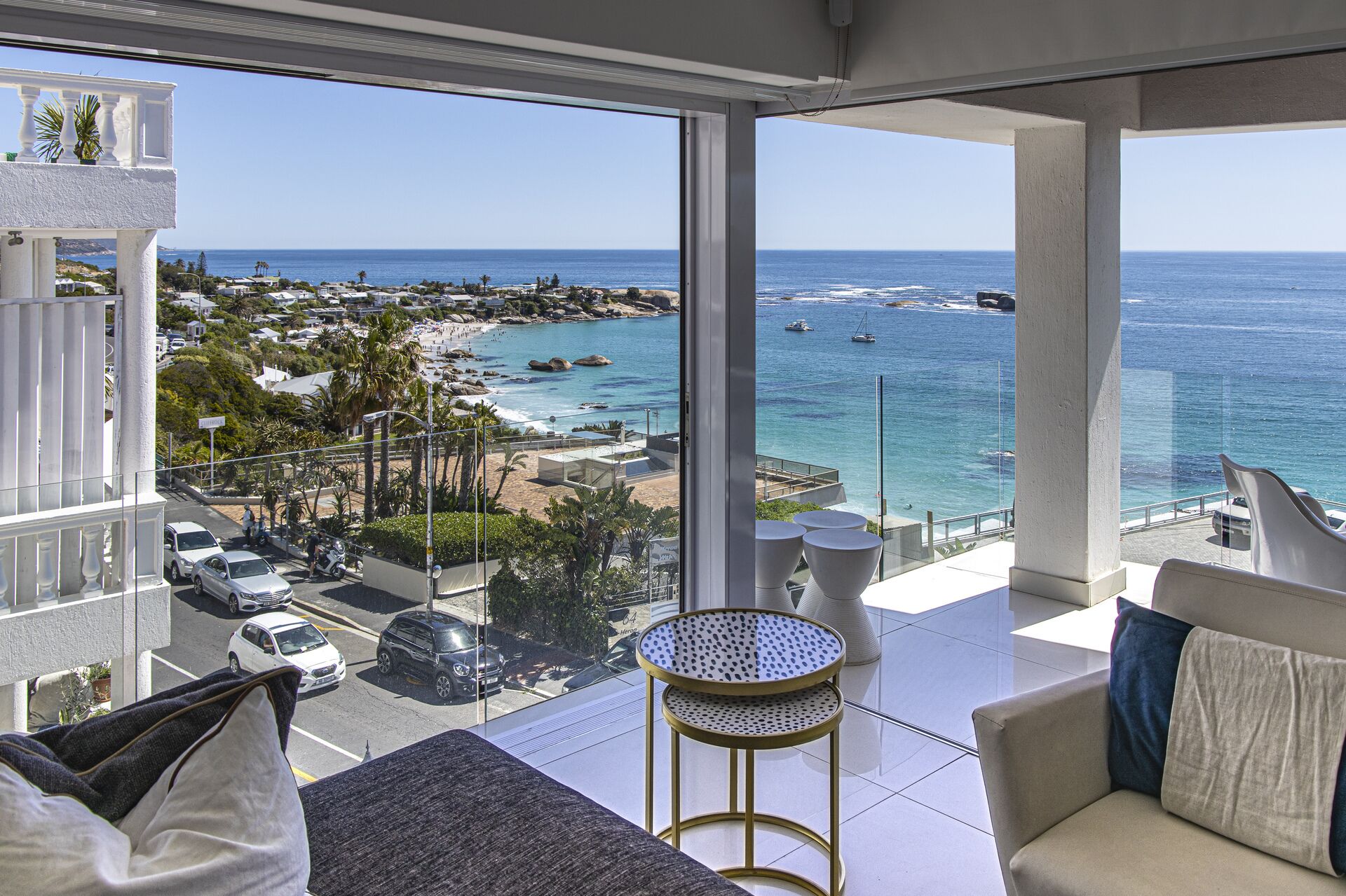Een balkon met uitzicht op strand en zee, met een ronde tafel en een bank.