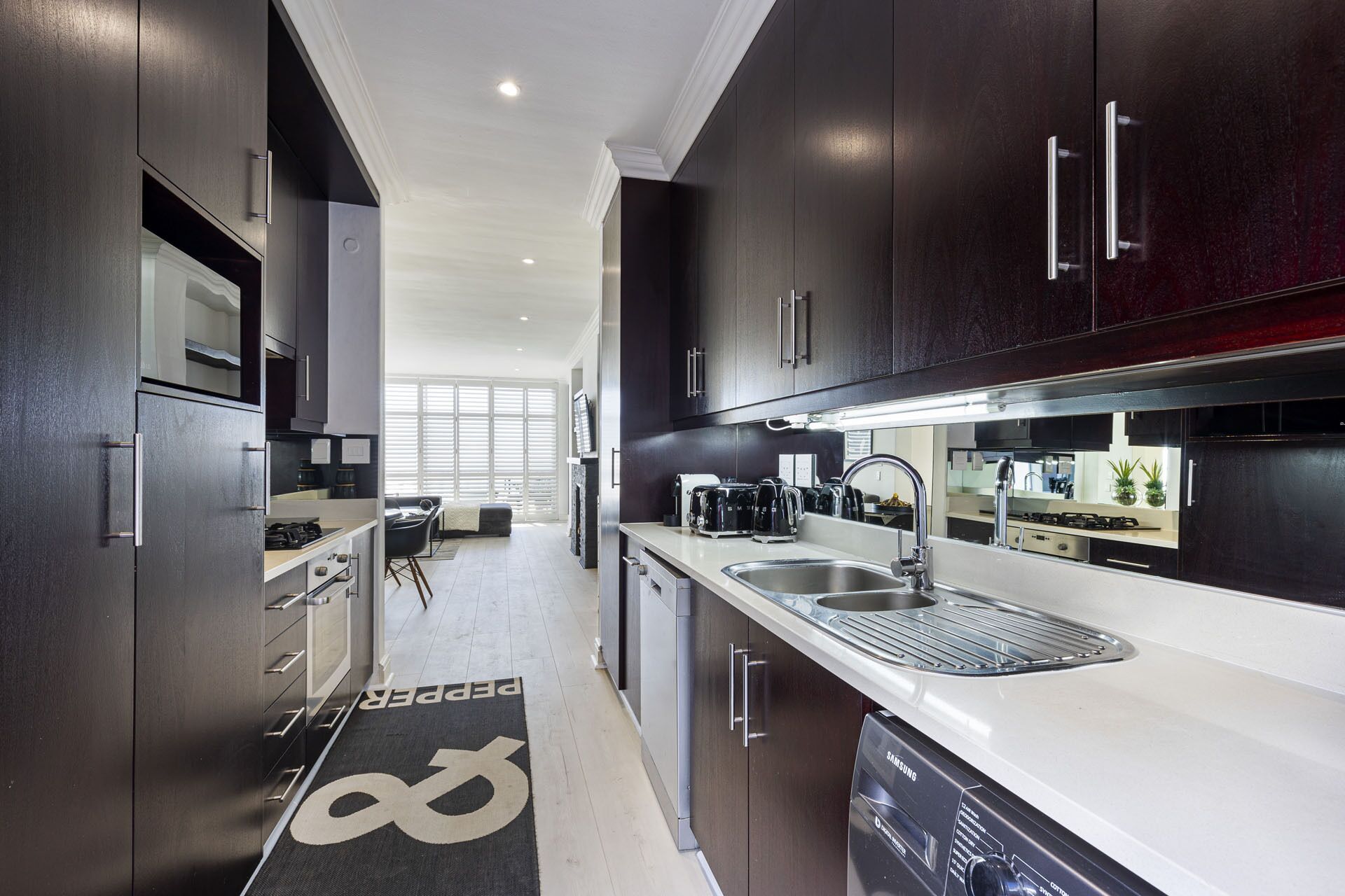 Una cocina moderna con armarios de madera oscura, electrodomésticos de acero inoxidable y un amplio ventanal que proporciona luz natural.