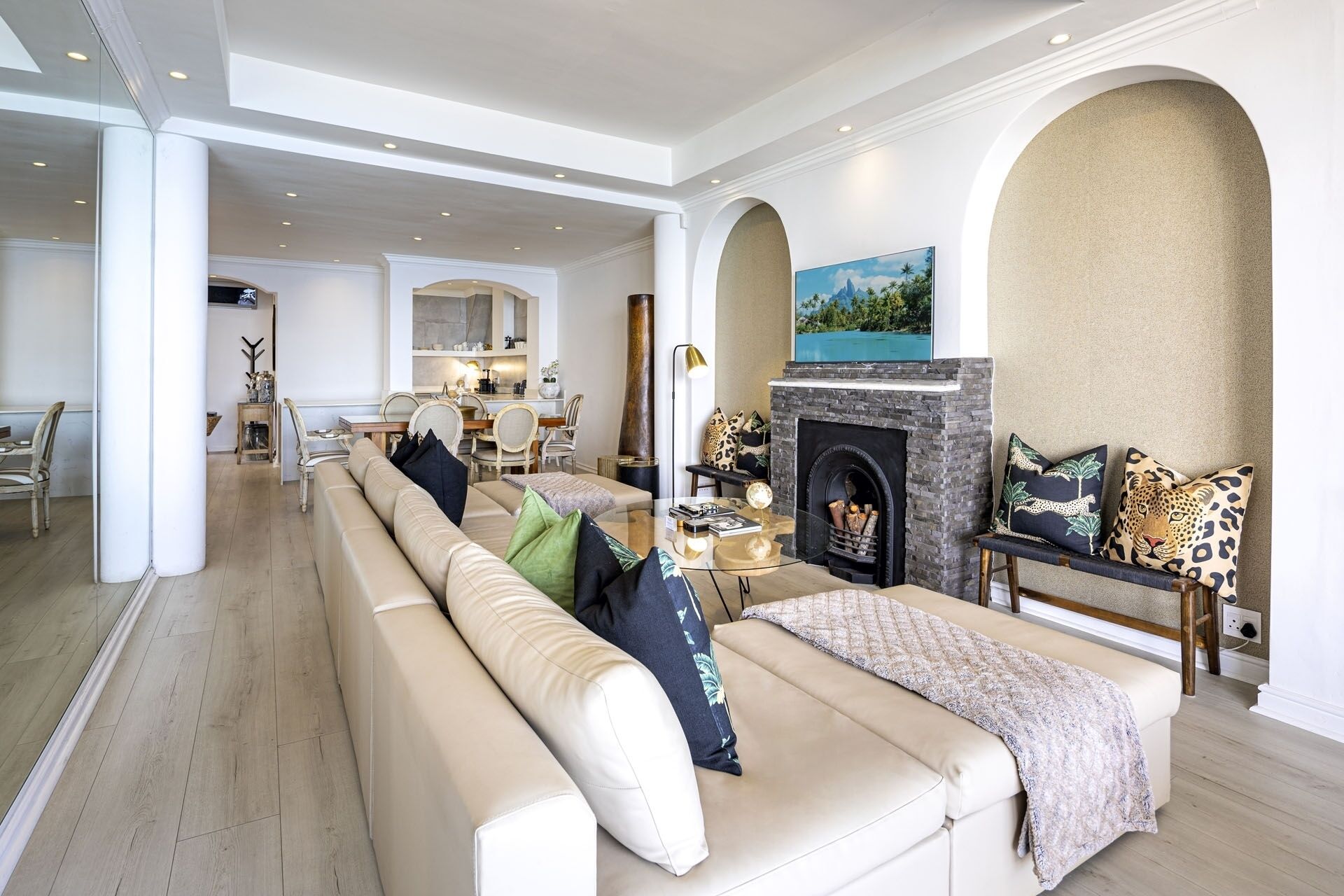Un salón amplio con un sofá color crema, una chimenea y un comedor al fondo.
