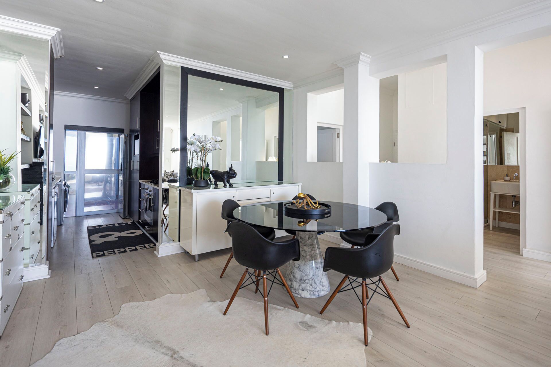 Un espace repas moderne avec une table ronde, des chaises noires et un socle en marbre.