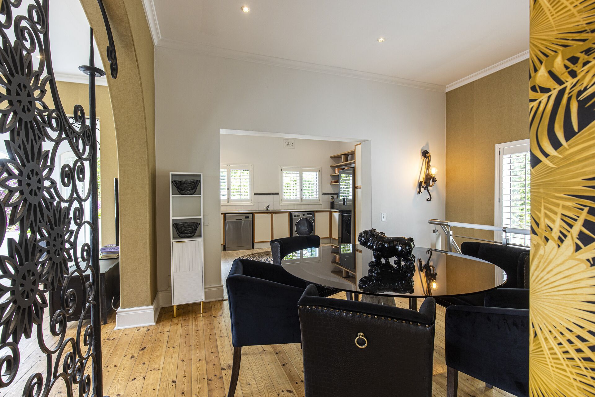 A modern kitchen with built-in appliances, a dining area with a round table and chairs, and a decorative metal partition.
