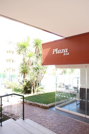 A building with a sign reading 'Plaza BAR' and a glass entrance.