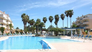 Une piscine avec des chaises longues et des palmiers.