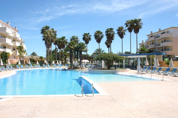 A swimming pool with lounge chairs and palm trees.