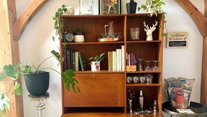 A wooden bookshelf with various items including books, decorative objects, and plants.