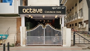A hotel entrance with a gated entrance, a sign reading "octave CHURCH INN", and a building in the background. - Octave Church Inn (Bengaluru)