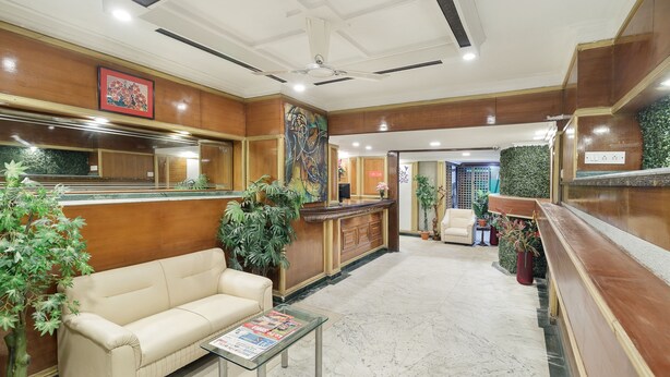 A hotel lobby with a reception desk, a sofa, a coffee table, and several potted plants. - Octave Church Inn (Bengaluru)