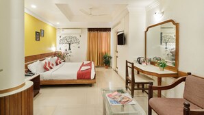 A hotel room with a bed, a desk, a chair, a mirror, and a television. - Octave Church Inn (Bengaluru)