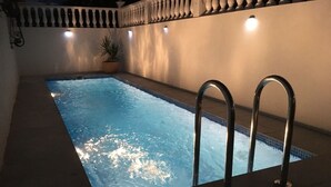 A swimming pool with a metal ladder, surrounded by a tiled deck and a white wall with a balustrade. - Immaculate 2-bed Villa With Pool in Mazarrón (Mazarrón)