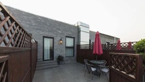 A patio area with a table and chairs, a potted plant, and a wooden fence. - Yiting Zhenshe Hotel (Beijing)