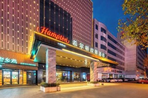 A hotel with a prominent marquee sign, multiple floors, and a well-lit entrance area.