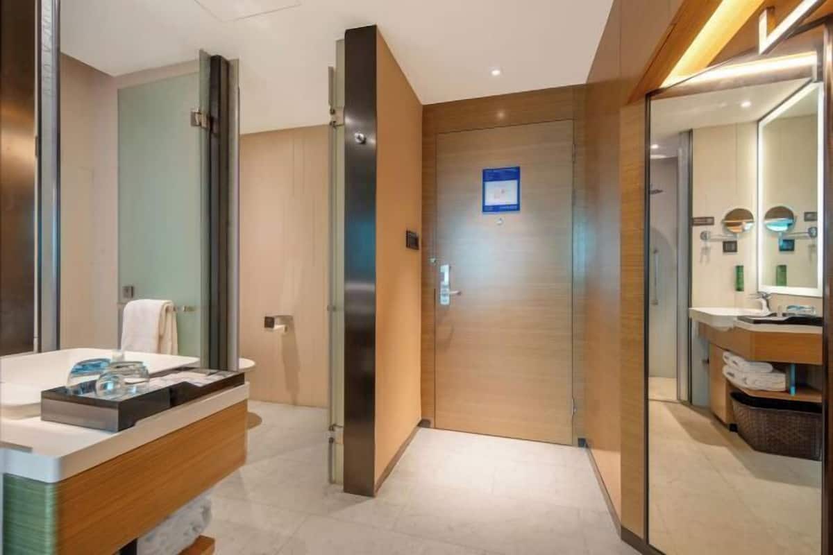A modern bathroom with a wooden vanity, a glass shower enclosure, and a mirror with a sink.