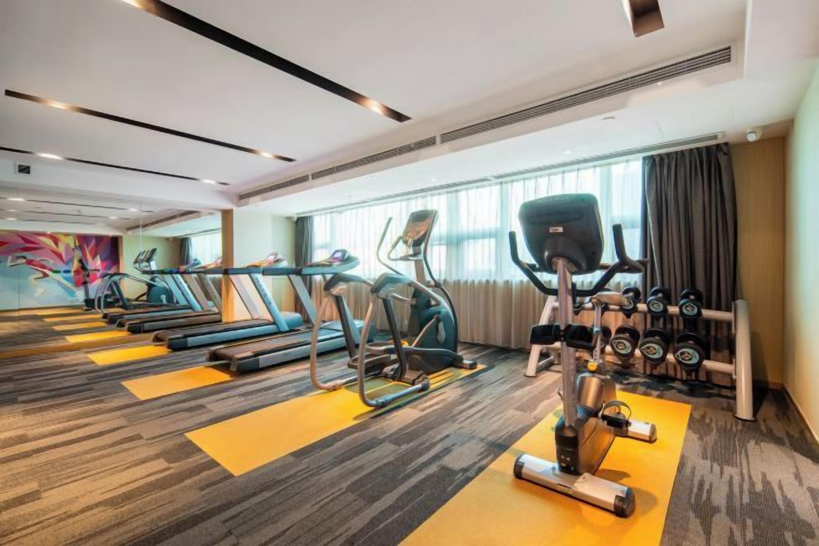 A hotel gym with treadmills, elliptical machines, and free weights.