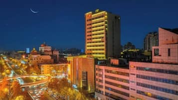 A cityscape at night with illuminated buildings and a crescent moon in the sky.