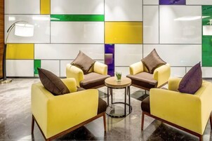 Un área de descanso moderna con sillones amarillos, una mesita redonda y una lámpara de pie.