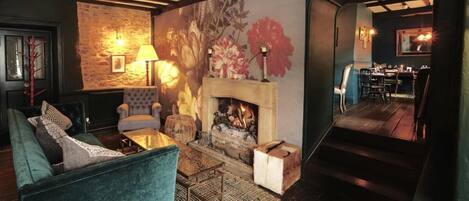 A cozy living room with a fireplace, a sofa, and a dining area visible through an archway.