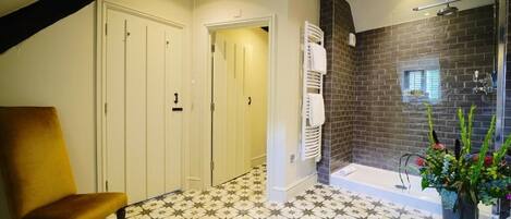 A bathroom with a star-patterned floor, a bathtub, a shower, and a potted plant.