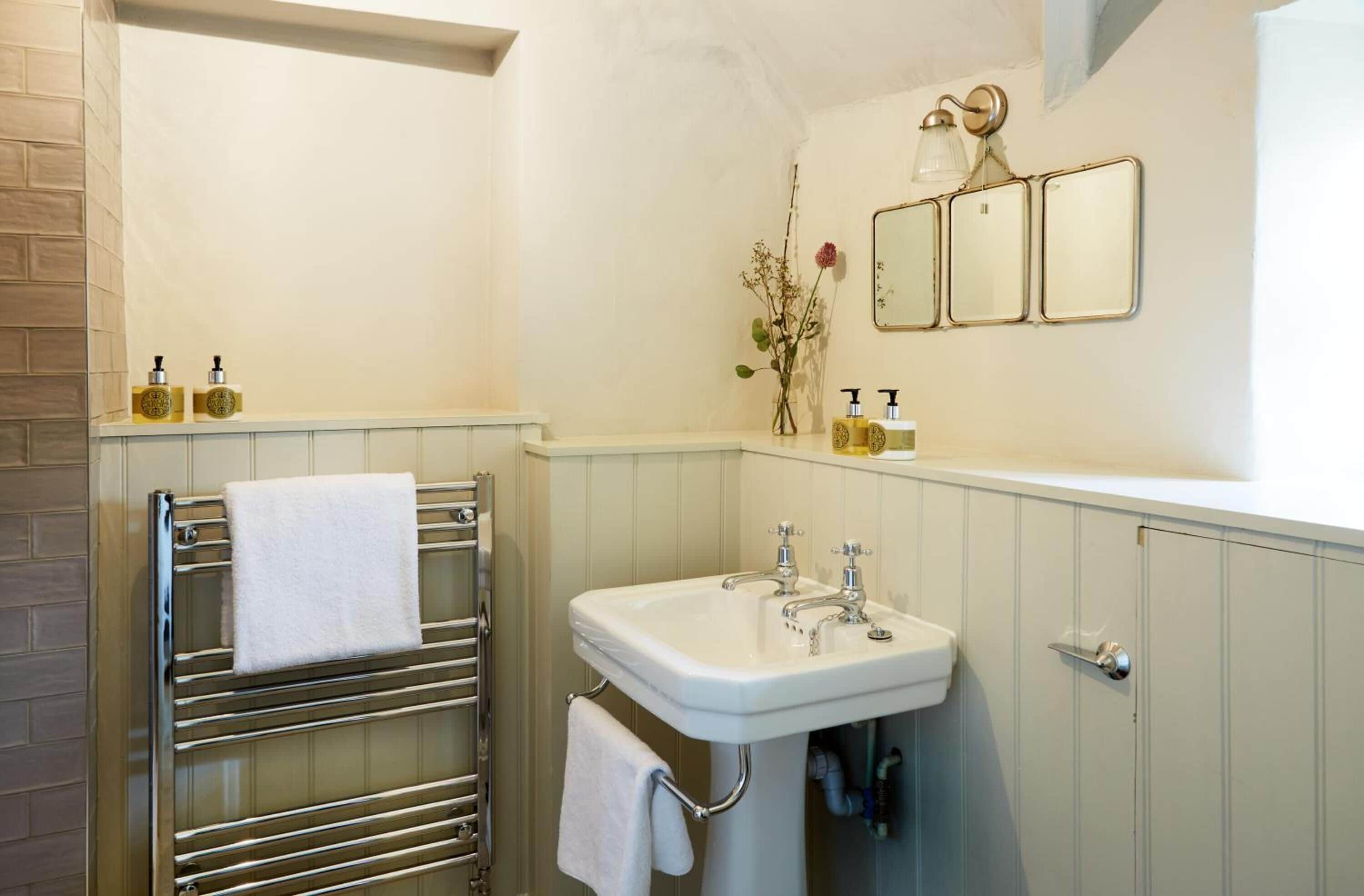 A bathroom with a white sink, a towel rack, and a mirror.