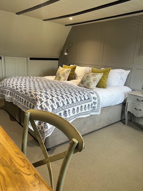 A modern bedroom with a bed, bedside tables, and a chair. - The Bull Hotel (Fairford)