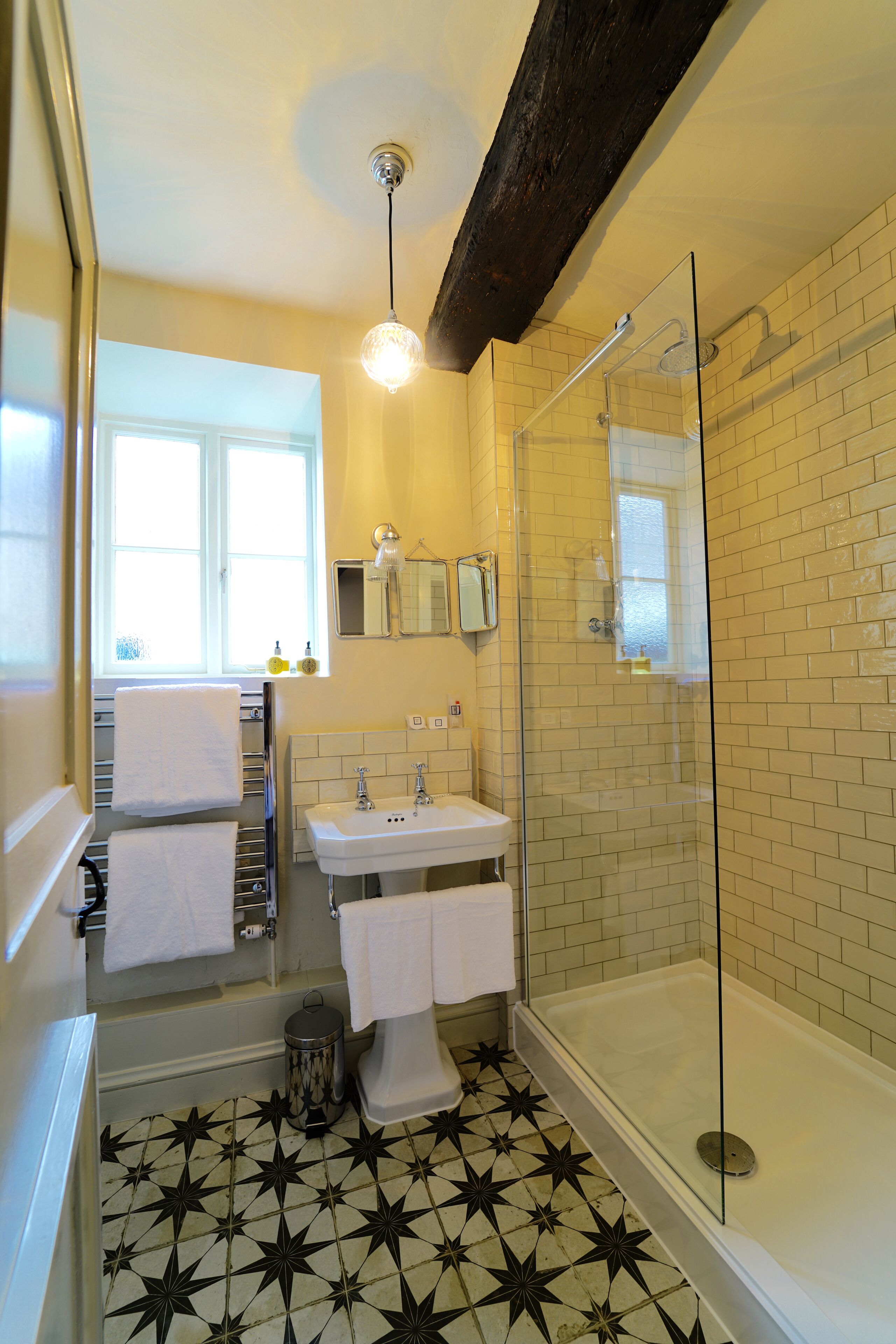 A bathroom with a shower, sink, and a window.