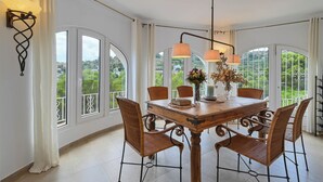 A dining area with a wooden table, wicker chairs, and a chandelier.