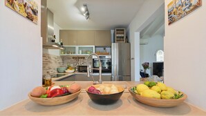 A kitchen with a central island, a stainless steel refrigerator, and a window.