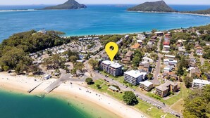 An aerial view of a coastal town with a prominent building marked by a yellow pin. - Florentine, 14/11 Columbia Cl - – AIRCON, WIFI, UNSURPASSED WATER VIEWS (Nelson Bay)