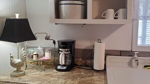 A kitchen with a coffee maker, a cabinet with glassware, and a sink with a soap dispenser. - House: Lower  prices! Snowbirds Welcome!  Bring your boat for fall fishing (Beaufort)