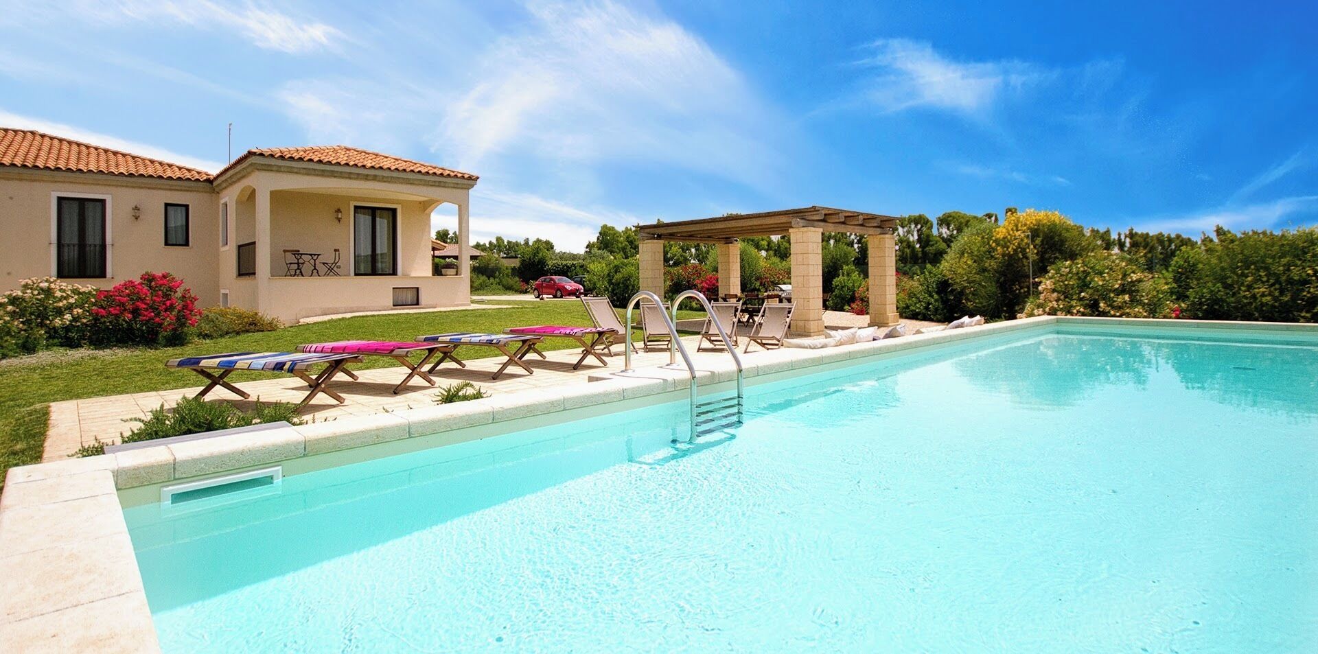 Une piscine avec des chaises longues et une pergola.