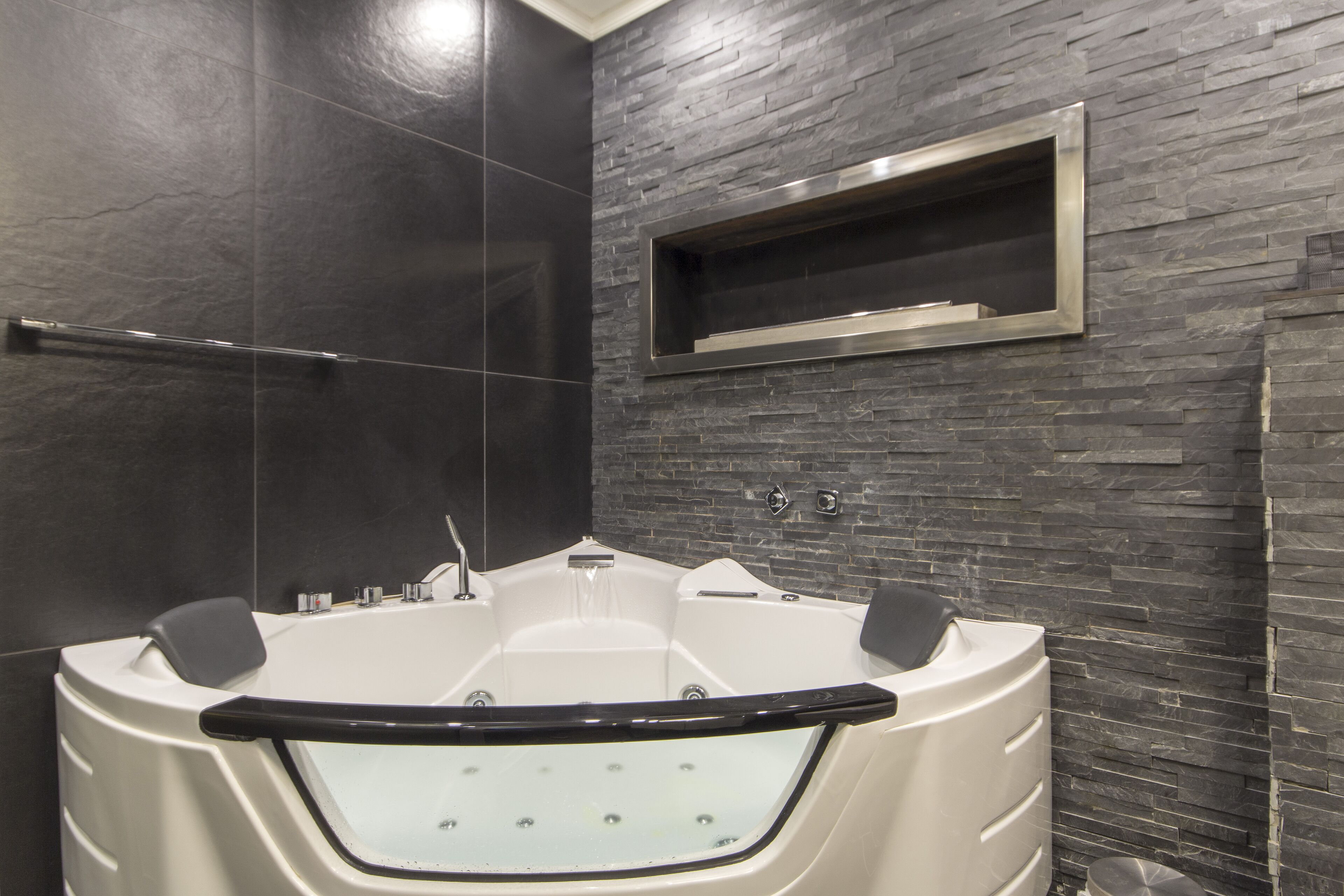 Un baño moderno con una bañera independiente, ducha con mampara de vidrio y estante empotrado.