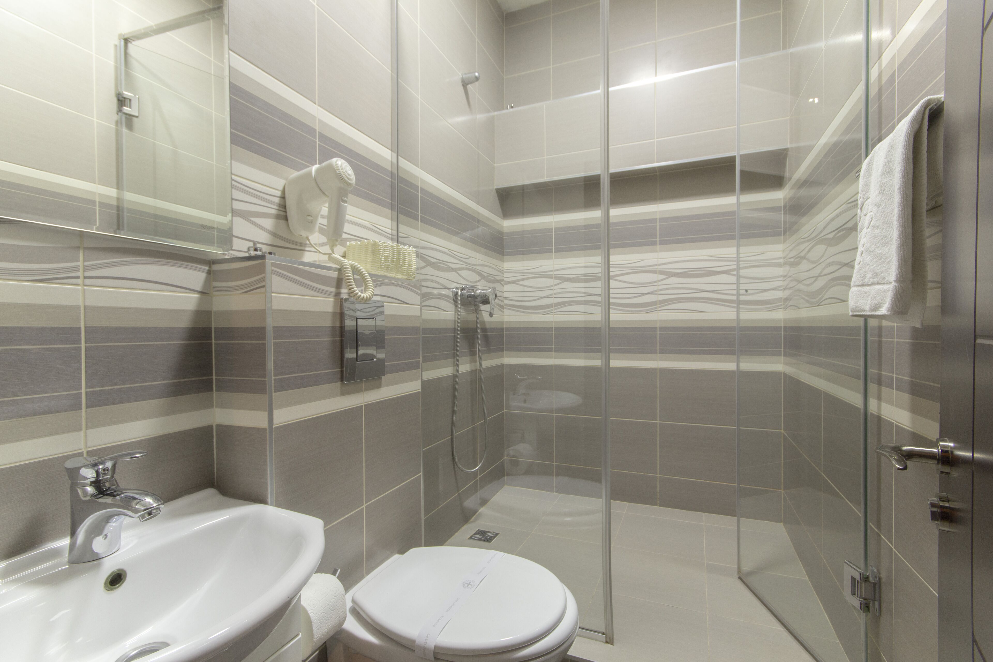 Un bagno con cabina doccia in vetro, lavandino e water.