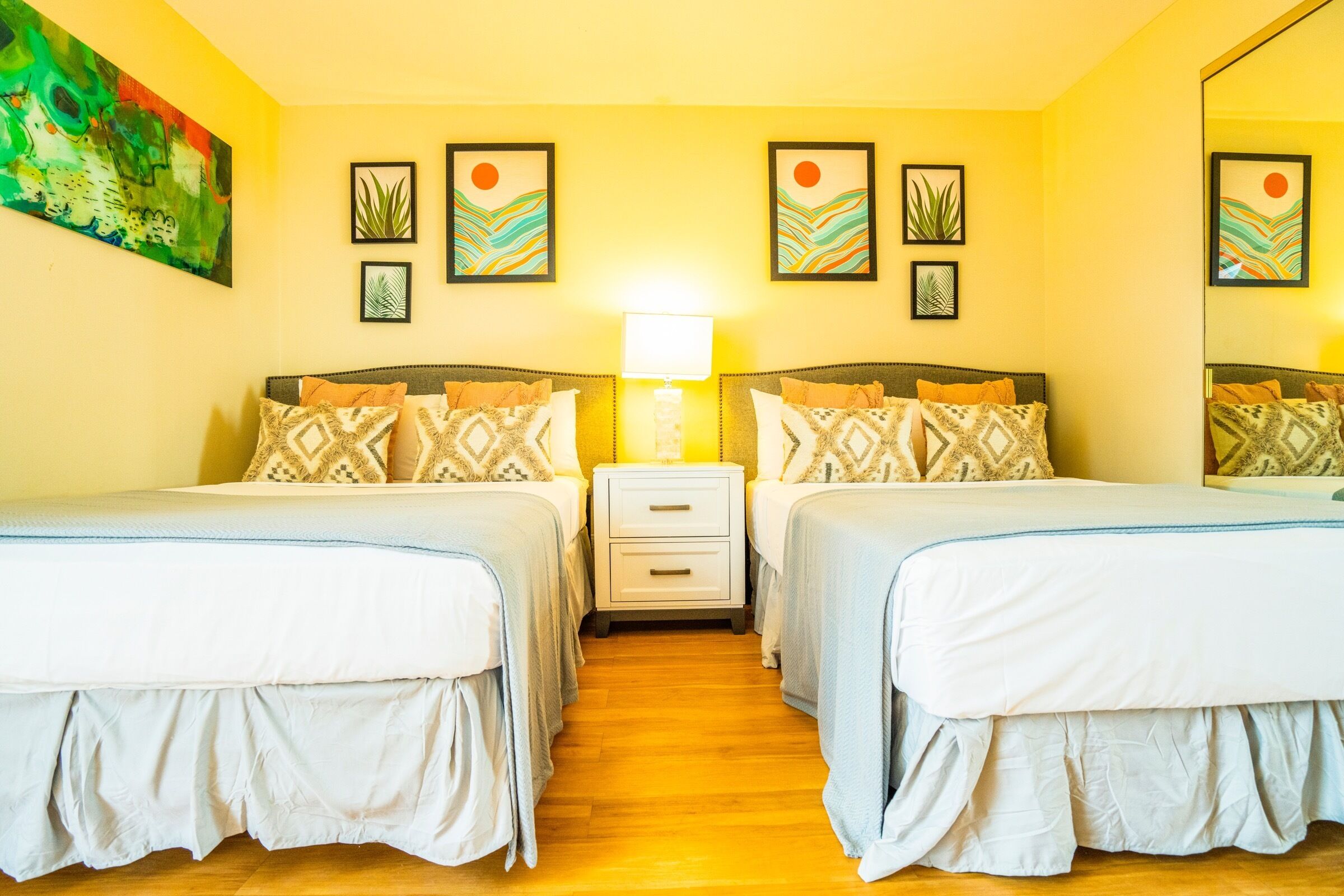 Una habitación de hotel con dos camas, una mesita de noche y una lámpara fijada a la pared.