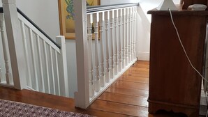 Eine Holztreppe mit weißen Geländern, einem Holzboden und einem gerahmten Bild an der Wand.
