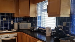 Eine Küche mit Holzausstattung, einer Mikrowelle, einem Toaster, einem Wasserkocher und einem Spülbecken.