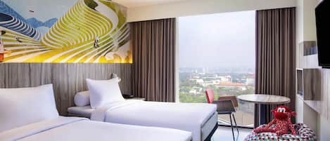 Habitación de hotel con dos camas, vista a la ciudad, una mesa redonda y un sillón de pie colorido.