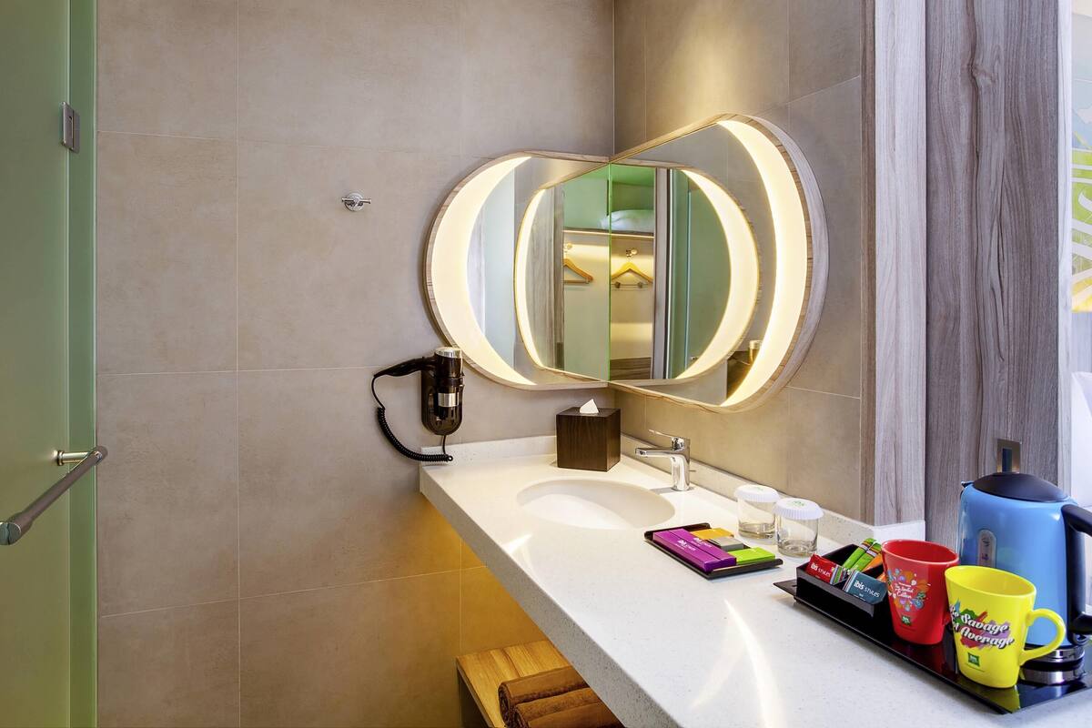 A modern bathroom with a large mirror, a sink, and a towel rack.