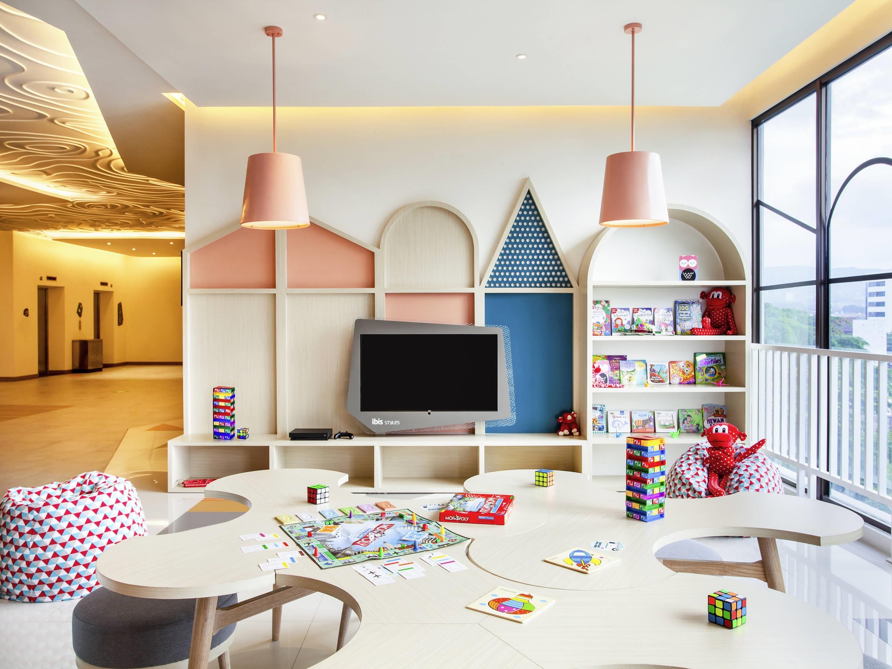A modern children's playroom with a TV, bookshelves, and various toys.