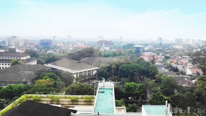 A cityscape with a swimming pool in the foreground, surrounded by buildings and greenery. - ibis Styles Bandung Grand Central (Bandung)