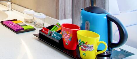 A kitchen counter with a coffee maker, a tray with coffee pods, and a mug.