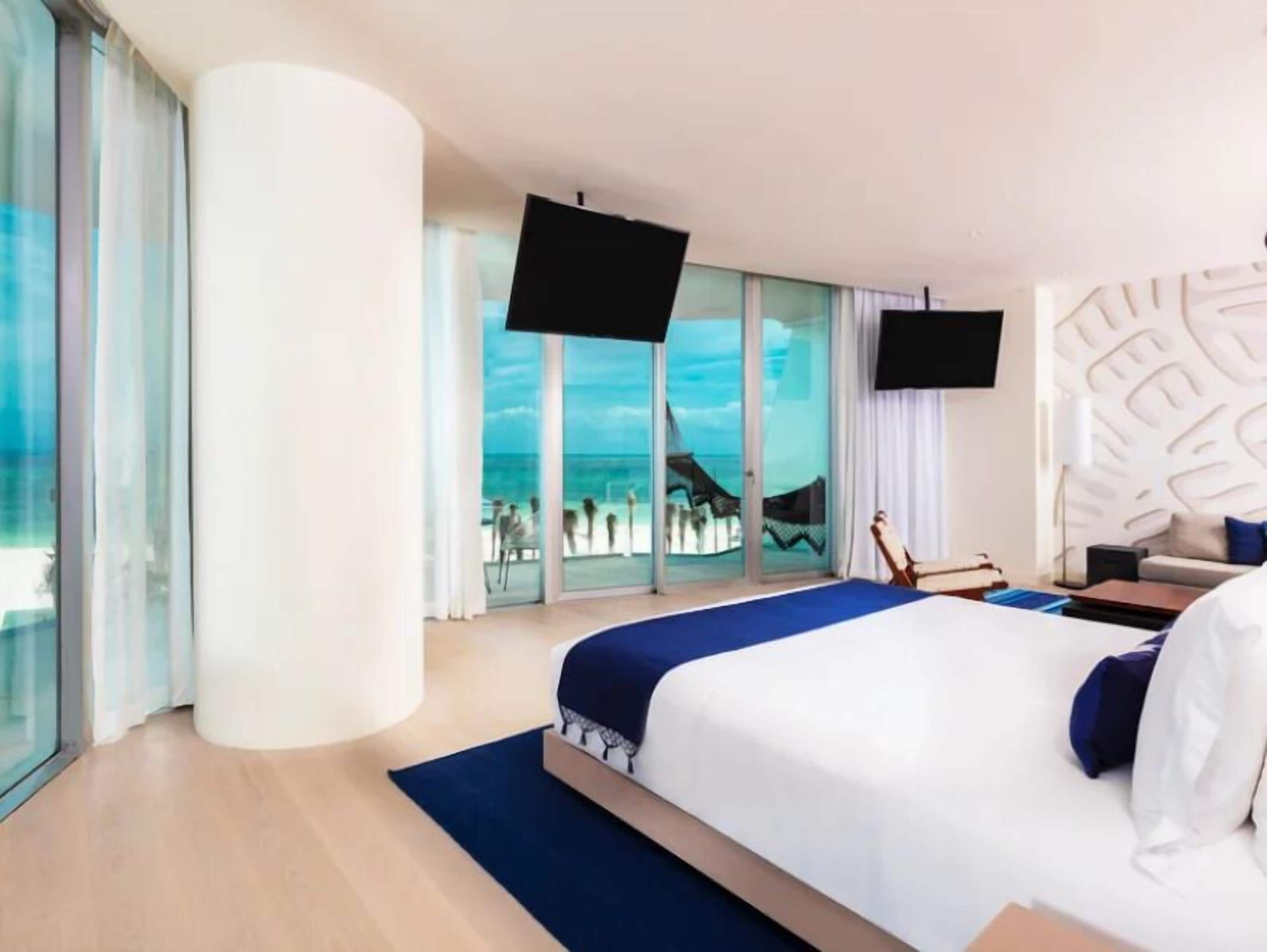 Habitación de hotel moderna con una cama grande, televisión de pantalla plana y balcón con vistas a la playa.