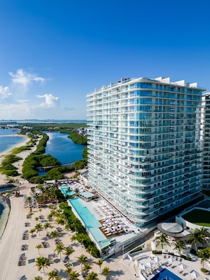 A high-rise hotel with a pool area, beach access, and views of the ocean. - SLS Cancun (Cancun)
