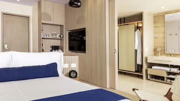 Et moderne hotelværelse med en stor seng, fjernsyn, et garderobeskab og et badeværelse med spejl og håndvask.