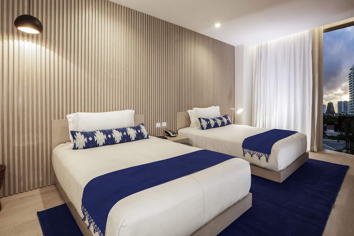 Ein Hotelzimmer mit zwei Betten, Blick auf die Stadt und modernem Design.