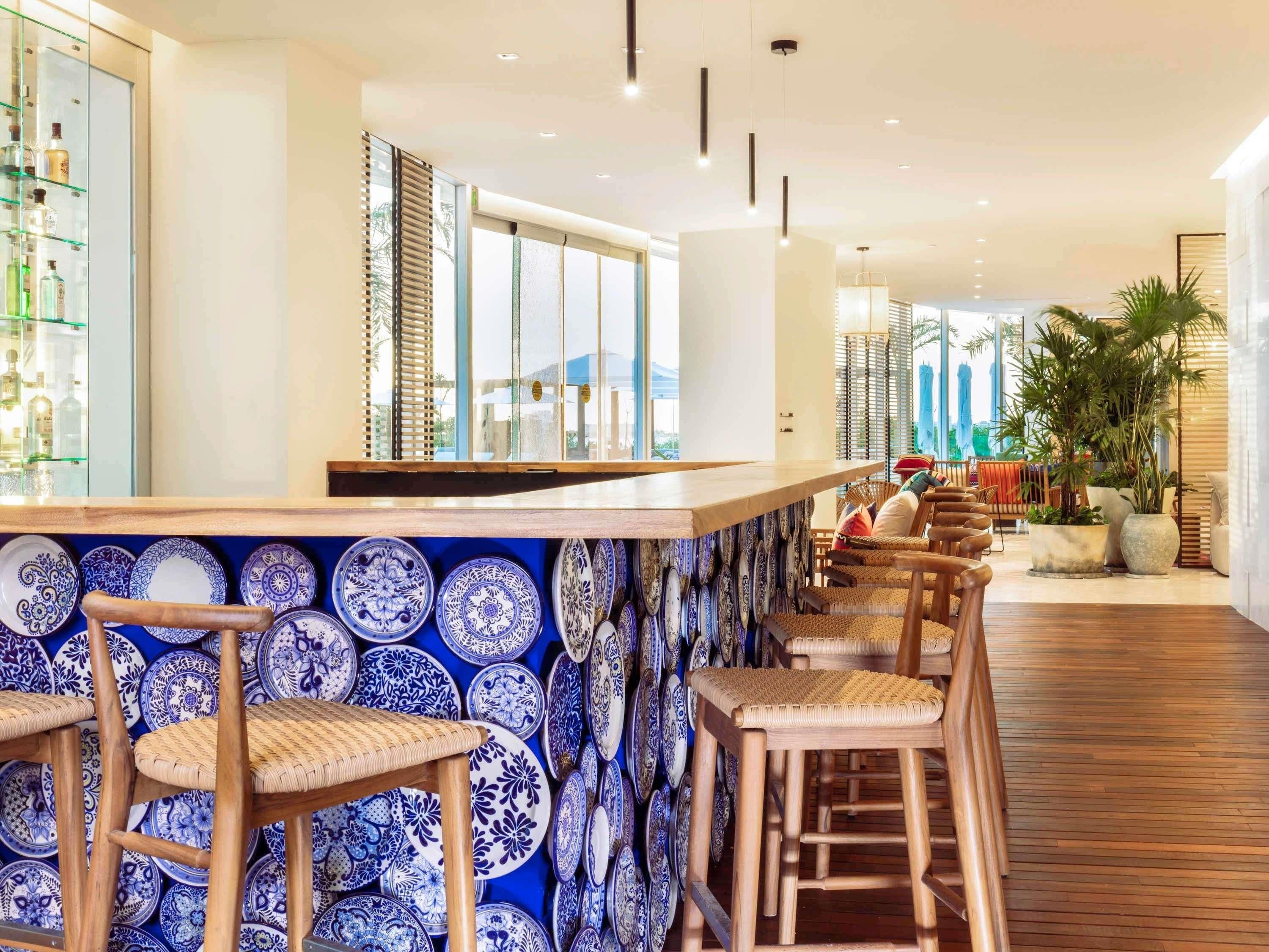 Un espace bar avec un mur décoré de motifs, des tabourets en bois et un comptoir.