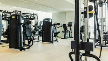 A modern gym with various exercise machines, large mirrors, and a clean, spacious layout.