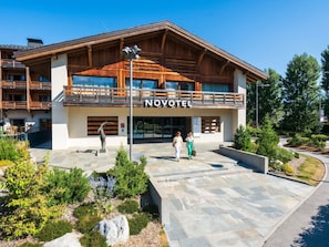 Un hotel con fachada de madera, balcones y un acceso empedrado de piedra.