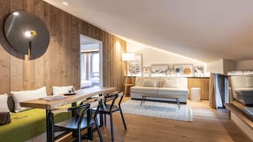 Un salon moderne avec un mur en bois, un coin repas comprenant une table et des chaises, un canapé et une table basse.