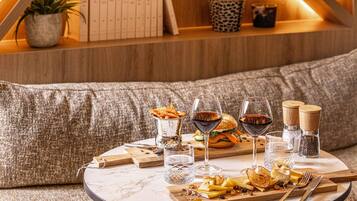 A round marble table with a cheese platter, wine glasses, and cutlery.