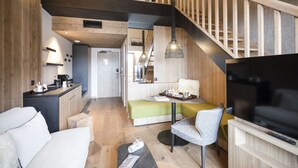 Un espace de vie moderne comprenant un canapé, une table à manger, un téléviseur et un escalier.